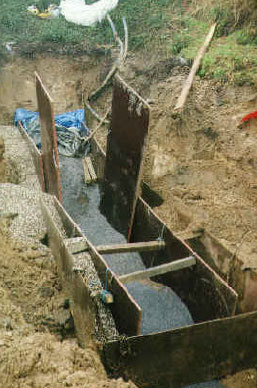 Figur 7 Væggen på Hårdkrom-grunden under konstruktion. Billedet viser gravekassen, hvor i jernspånerne placeres i midten med gruslag på begge sider.