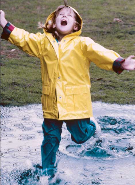 Pige løber i vandpyt i regnvejr