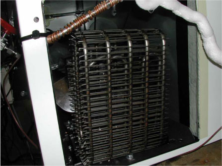 Figur 6 Den første del af gaskøleren er leveret af Bundy A/S. der er tale om en bukket wire on tube-”kondensator”. Både denne og kompressoren bliver kølet af en blæser, som også anes bagved.